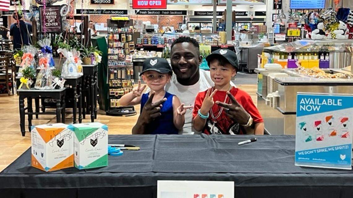 Former Carolina Panthers player Thomas Davis poses for a photo with two young fans at Harris Teeter in Ballantyne on Thursday night.