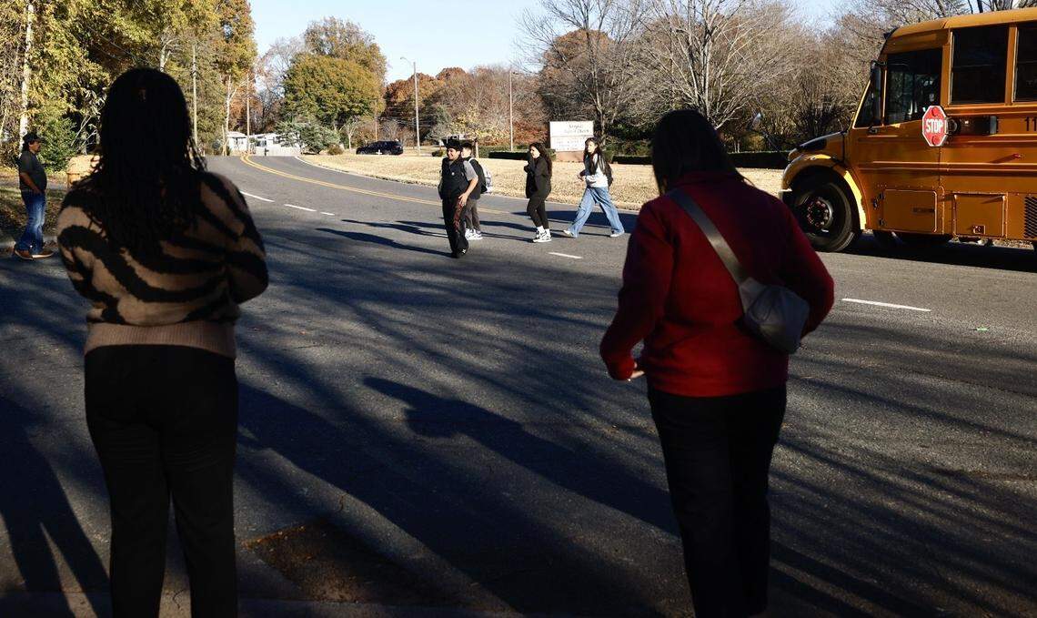 Concerned adults gather at a bus stop to help ensure kids get off the school bus safely in the Berryhill area.
