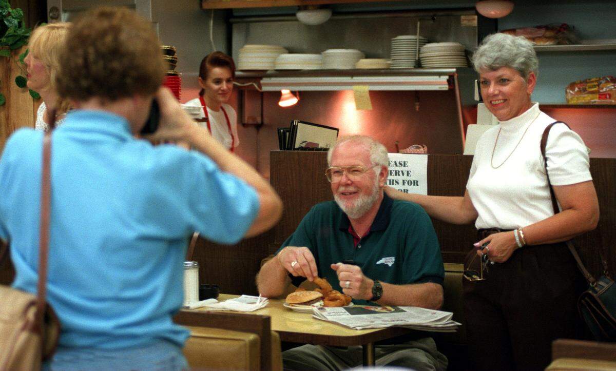 Pat Williams left, a regular customer at the Stanley Drug lunch counter, takes a picture of Ray and Carroll Purgason, who ran the post office at the drugstore, on August 21, 1997, the last day of operation for the counter. The Purgasons were to lose their jobs when the Post Office closed, as would Jim and Theodora Apostolou, who ran the lunch counter. Regulars gathered to photograph and sign a card in preparation for the sale of the local Stanley Drug Store on 7th Street to Revco.