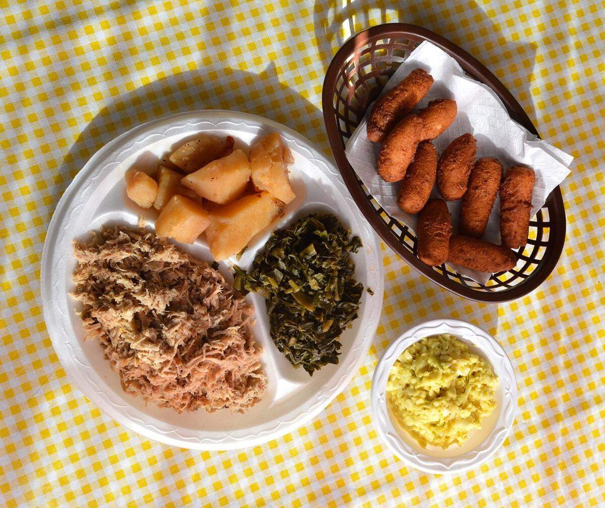 Pork barbecue plate with sides including barbecue potatoes, collards, slaw and hush puppies at Bill Spoon's Barbecue.