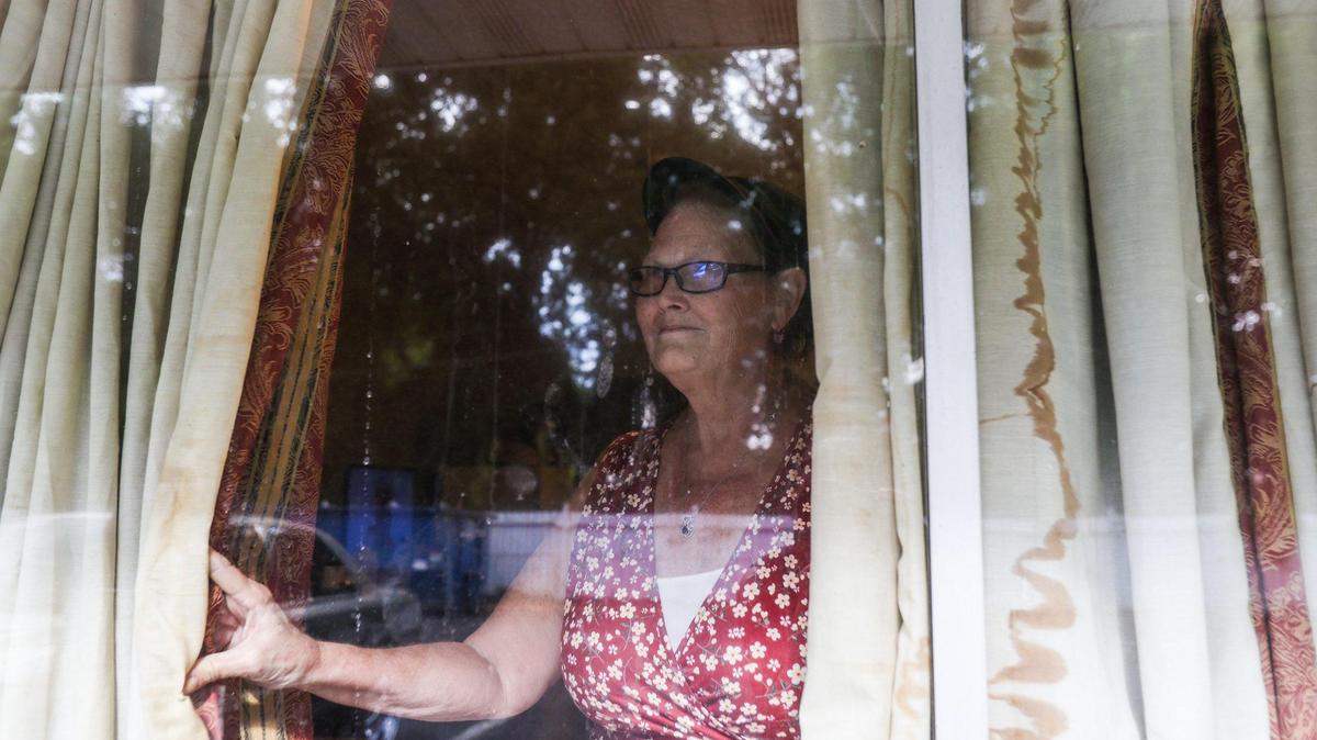 Kymber Means peers through water stained curtains in her room at the Southern Comfort Inn on Monday, June 27, 2022 in Charlotte, NC. Means, along with other residents at the hotel, is being made to move due to the hotel closing. Several residents have been living in the hotel in squalid conditions including signs of mold, bug infestations and water damaged curtains and carpets.