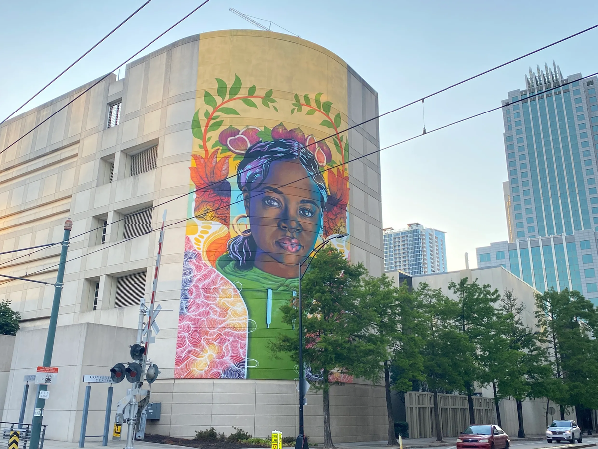 Sam Guzzie, along with fellow artists Owl and Kalin Renée Devone, worked on this mural in uptown across from the Charlotte Convention Center. It’s called “Where Inspiration and Strength Blooms.”