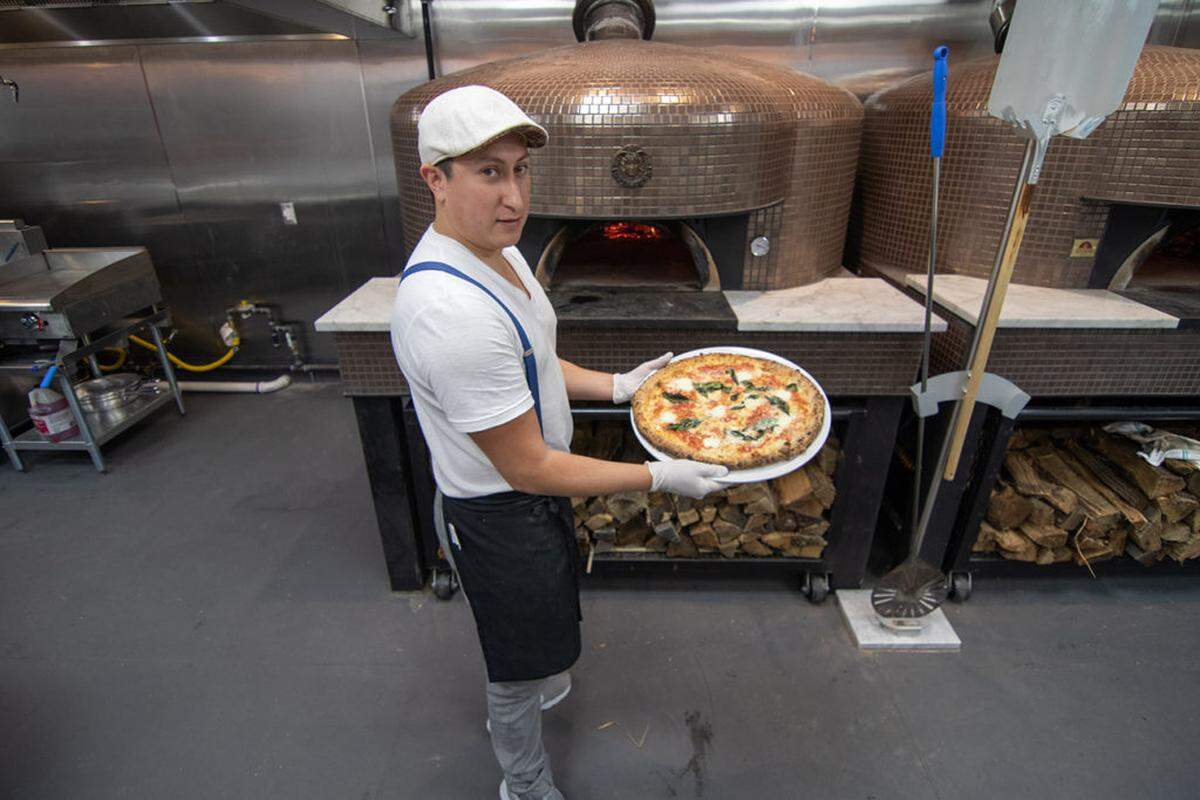 Capishe co-owner and head chef Alberto Moreno prepares a wood-fired margherita pizza.