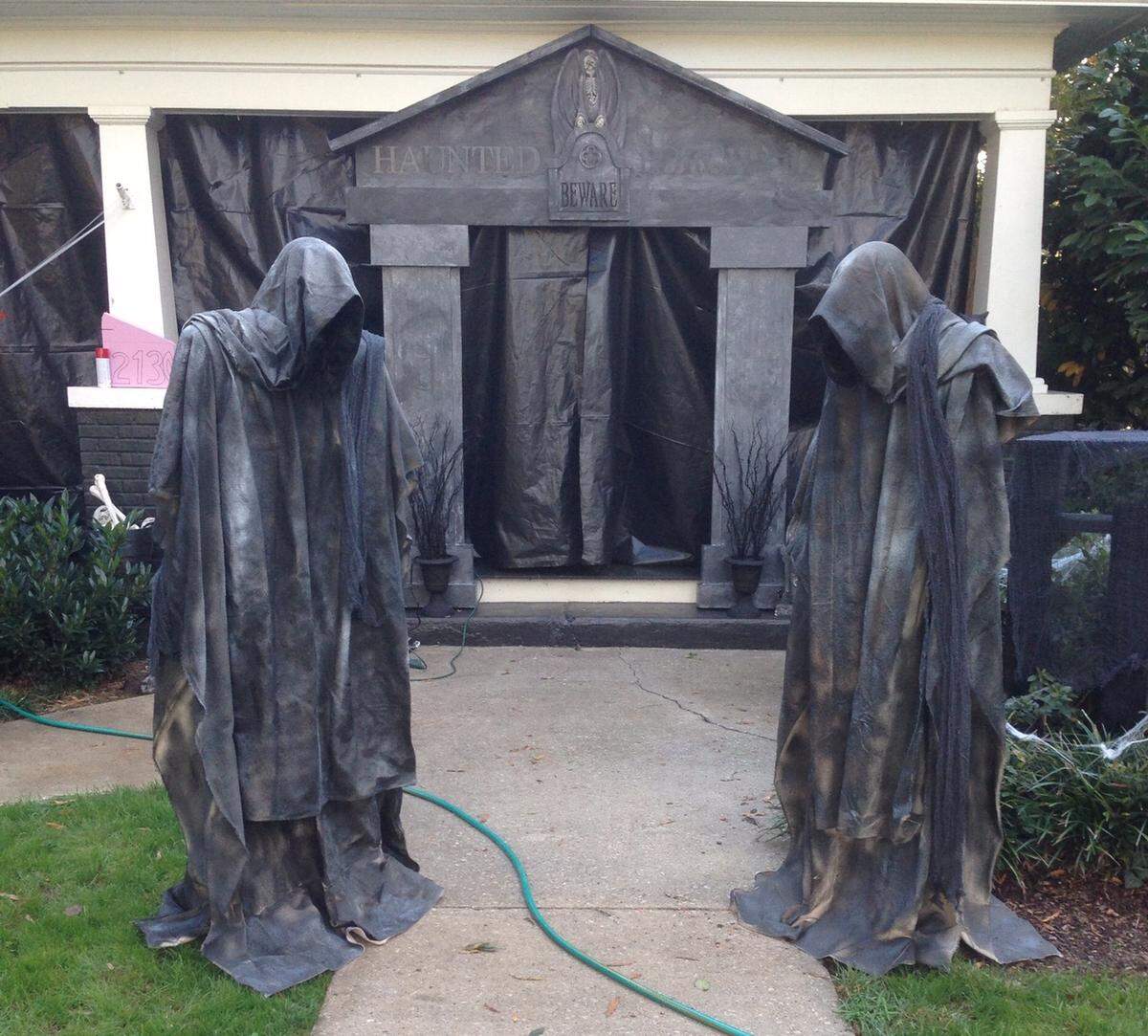 Kristen Johnson and Matthew Clark's first haunted porch, in 2013. The spooky figures were made out of posts, mannequin heads, and canvas tarps covered with truck bed lining, and the arch was constructed of pink insulation foam and latex paint. On the porch, which was enclosed with black plastic sheeting, they had about eight Halloween-store animatronics.