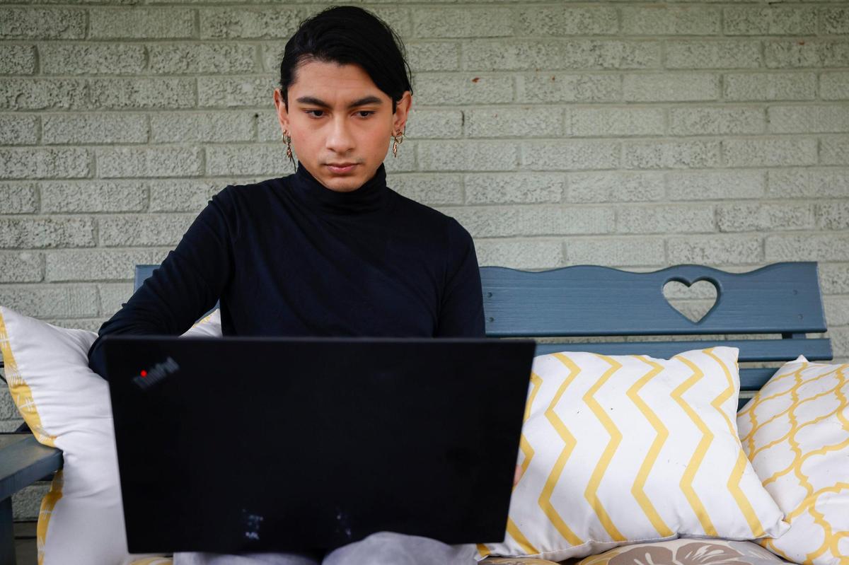 Arturo Pineda works on a laptop while sitting on their back porch in Charlotte. Pineda left their former job in 2021 , concerned about access to healthcare and other issues. Now Pineda works a paralegal at the Charlotte Center for Legal Advocacy.
