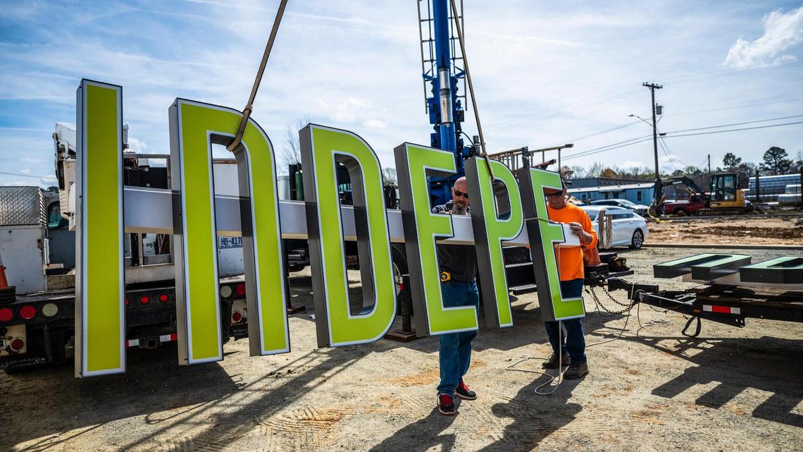 Jim Petty, left, and Gary Blanton with Gary’s Signs of Matthews on Tuesday prepare to hoist the Independent Picture House neon sign onto the Charlotte Film Society’s movie theater in NoDa.