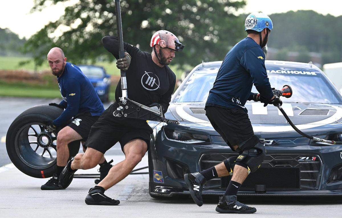 NASCAR driver Ross Chastain’s Trackhouse Racing pit crew members (L-R) Matt Simmons, Shane Wilson and Michael Roberts race around the car during pit practice on Tuesday, June 11, 2024.