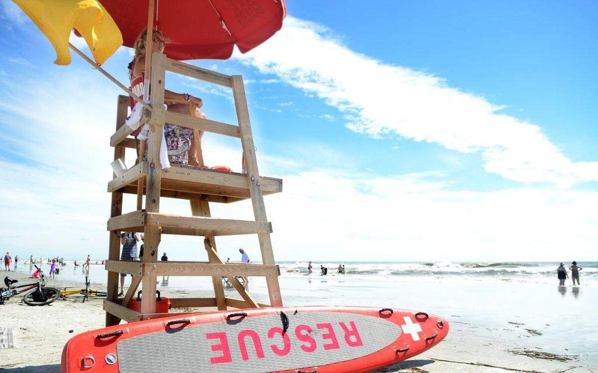A lifeguard stationed at the end of Coligny Beach Park access watches beachgeors on Monday, Sept. 25, 2017 as the yellow caution flag flies warning swimmers to expect strong surf churned by Hurricane Maria in the Atlantic.
