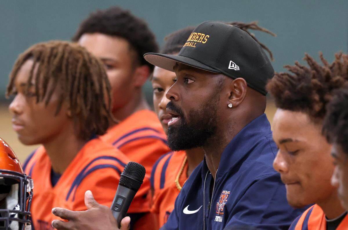 Julius Chambers High School head football coach Captain Munnerlyn, center, speaks during the Mecklenburg County Power 6 media day on Tuesday, August 5, 2025 at Independence High School.
