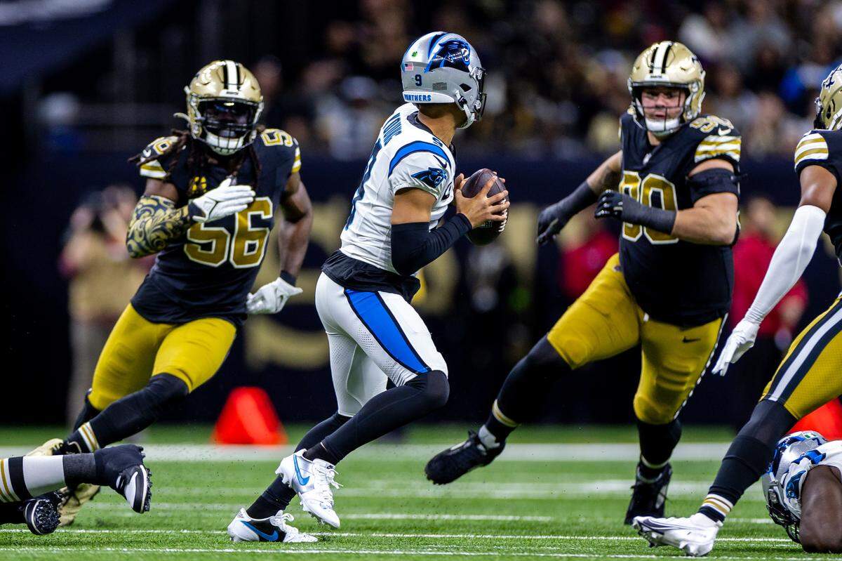 Carolina Panthers quarterback Bryce Young (9) is chased out the pocket by New Orleans Saints linebacker Demario Davis (56) and defensive tackle Bryan Bresee (90) during the first half at the Caesars Superdome.