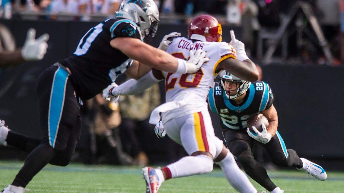 Panthers running back Christian McCaffrey, left, runs with the ball during the game against the Washington Football Team at Bank of America Stadium on Sunday.
