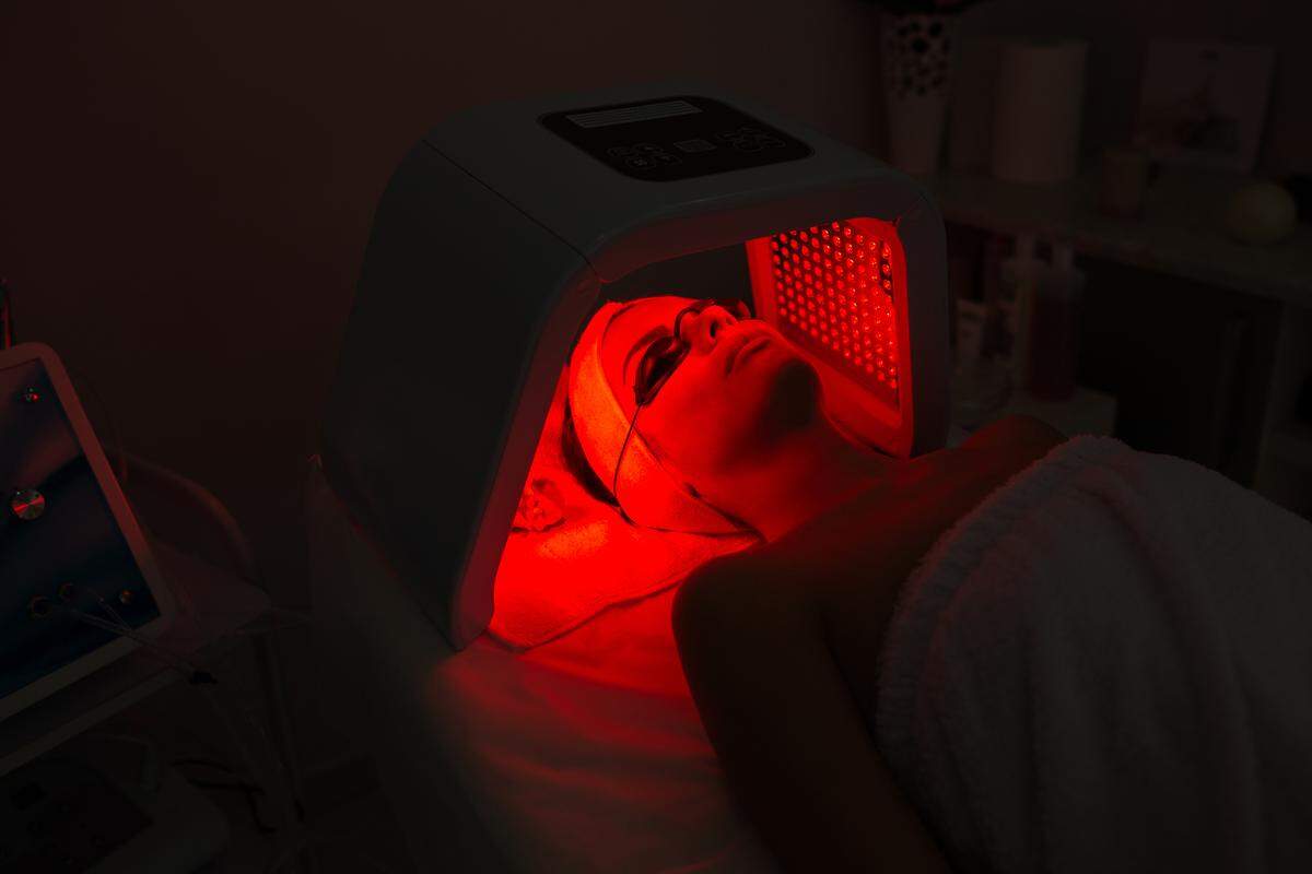 A woman receiving red light therapy on her face.