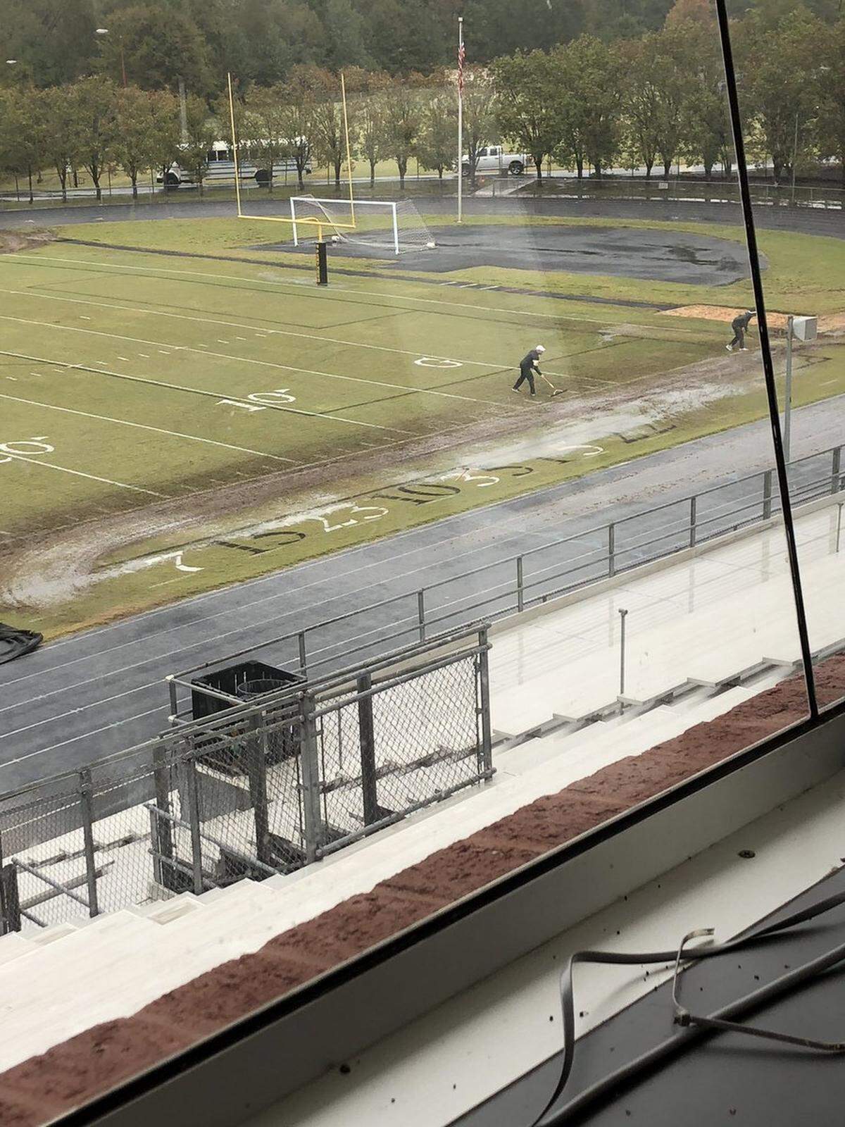 After CMS’ decision for schools to play Friday, workers at Providence High tried to clear the field for a game.
