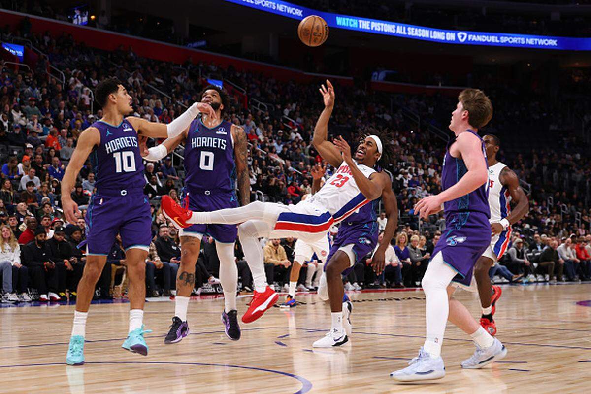 Jaden Ivey of the Detroit Pistons gets a shot off after taking a foul from Josh Green of the Charlotte Hornets during the first half at Little Caesars Arena in Detroit, Michigan.