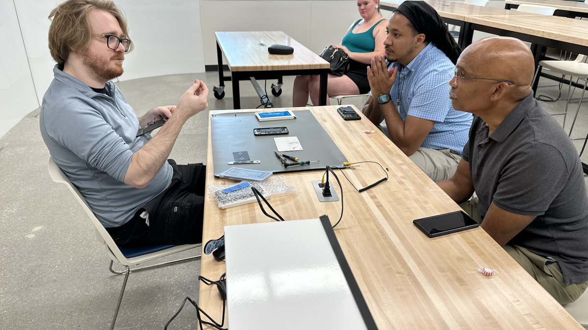 City Startup Labs founder Henry Rock, right, and other CSL team members observe head iFixAmerica instructor Alan Ramsay at Metropolitan Community College’s Fort Omaha Campus in Sept. 2023.