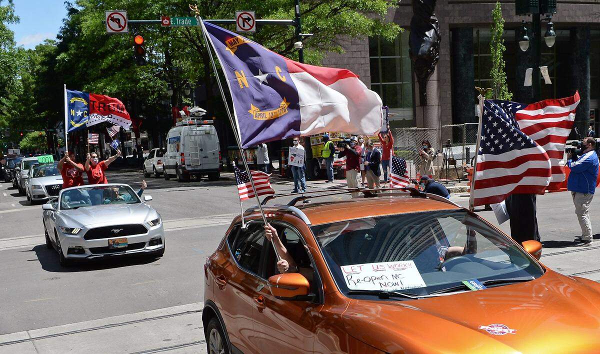 Participants in the Reopen Meck rally — organized by Maya Pillai — drive through the intersection of Trade and Tryon Streets in uptown Charlotte on May 1.