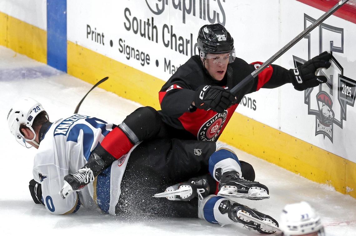 Cleveland Monsters Samuel Knazko, left, is pinned to the ice as Charlotte Checkers Wilmer Skoog, right, tries to move toward the puck during action at Bojangles Coliseum in Charlotte, NC on Friday, October 18, 2024.