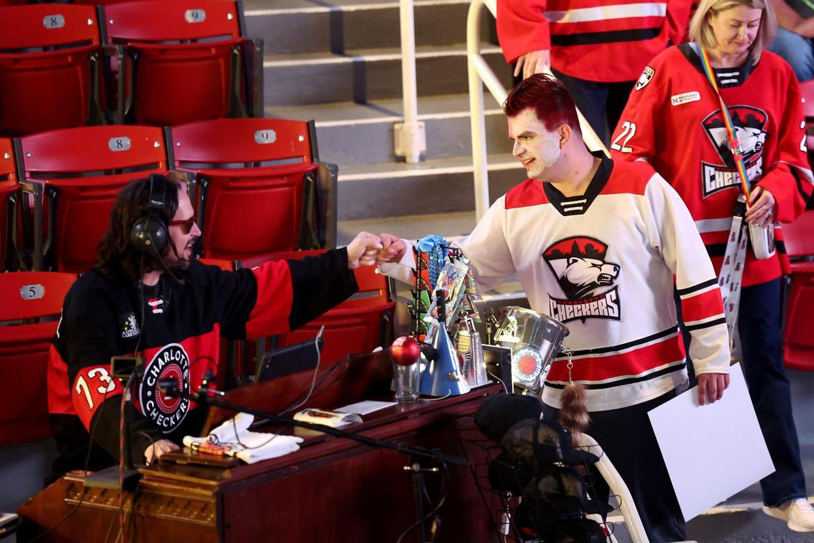 Greazy Keys, left, reaches out to bump fists with a Charlotte Checkers fan prior to the team’s game against the Cleveland Monsters game at Bojangles Coliseum in Charlotte, NC on Friday, October 18, 2024.