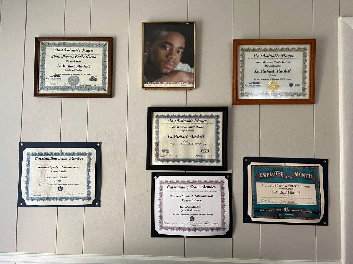 The wall in the living room of the Mitchells’ Charlotte home is decorated with LaMichael’s photo — and an array of his employee awards.