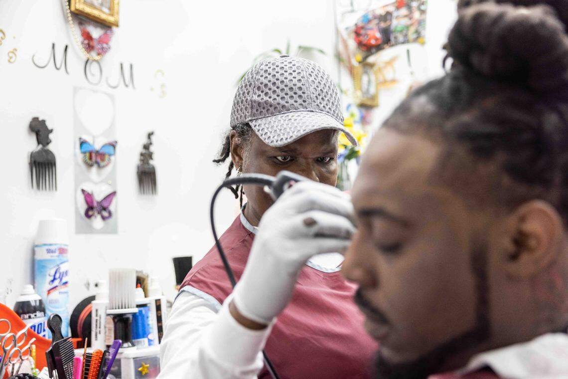Dee Baidoo (Lady D), left, cuts Dennis Anderson’s hair at Anderton Barber & Stylists in Charlotte.