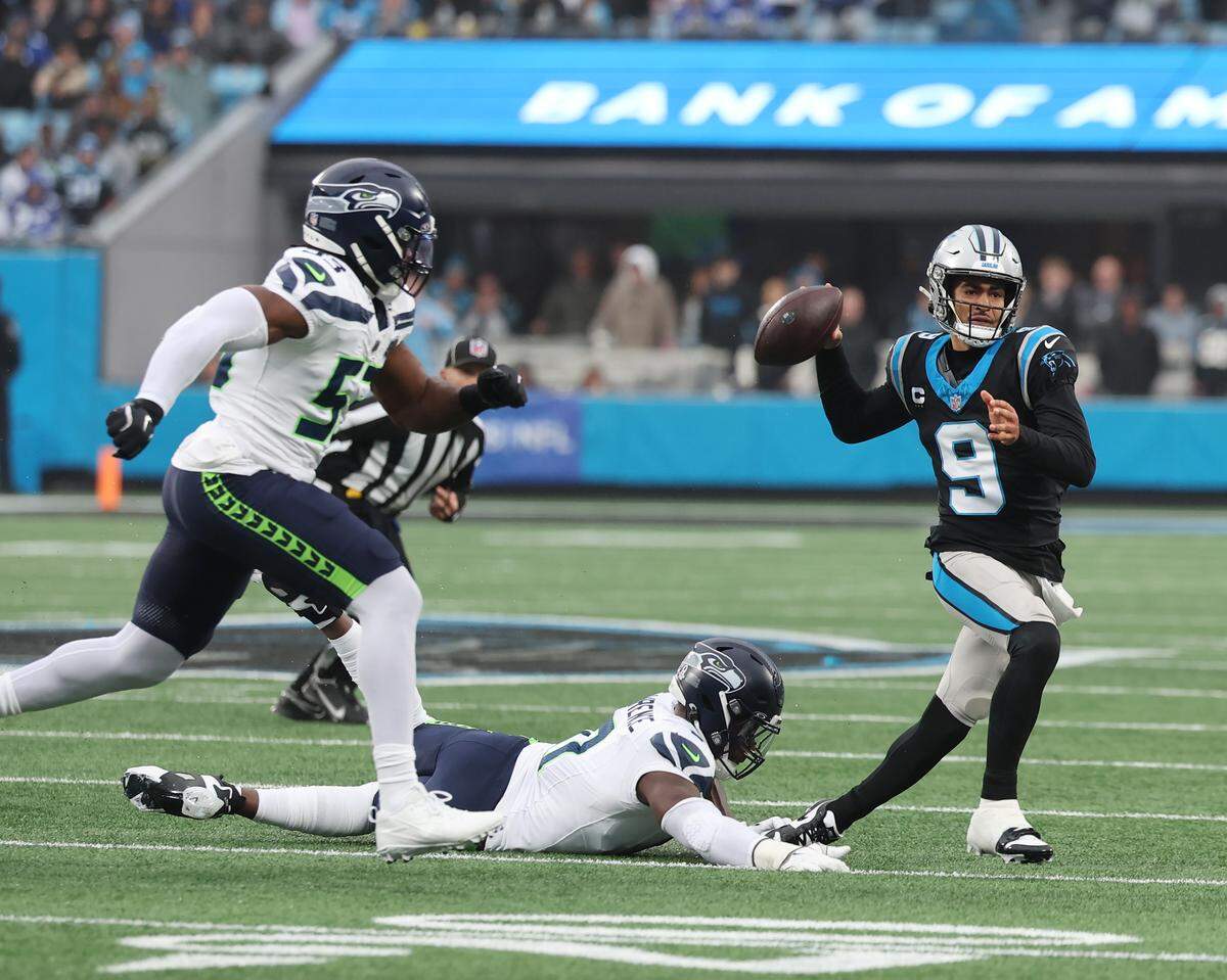 Carolina Panthers quarterback Bryce Young, far right, looks for an opening as he is pursued by Seattle Seahawks linebackers Boye Mafe, left, and DeMarcus Lawrence during Sunday’s game at Bank of America Stadium.