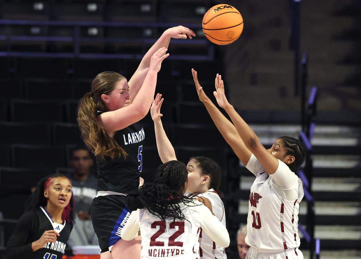 Lake Norman’s Kelsey Rhyne, left, passes the ball out to a teammate as the Wakefield defense converges on her during the girls NCHSAA 4A State Championship game on Saturday, March 15, 2025 at Lawrence Joel Veterans Memorial Coliseum in Winston-Salem, NC. Lake Norman defeated Wakefield 43-41.