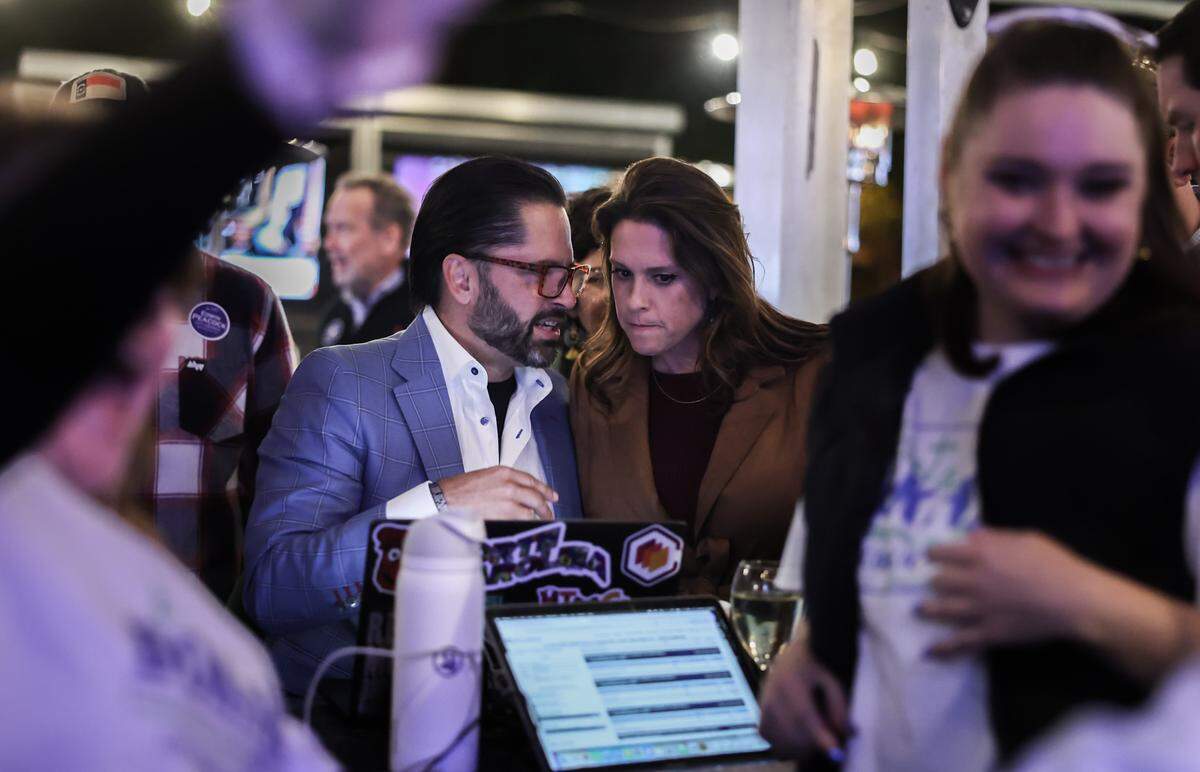 Tariq Bokhari, left and his wife, Krista, check election results during a watch party at Selwyn Avenue Pub in Charlotte, N.C., on Tuesday.