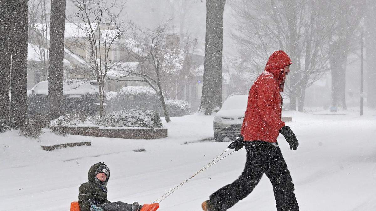 Charlotte-area schools are again announcing changes to Wednesday classes after a historic snow storm over the weekend. In this file photo, Jonathan Boone, right and son, Avett, left make their way along Lyon Court in Charlotte, NC on Saturday, January 31, 2026.