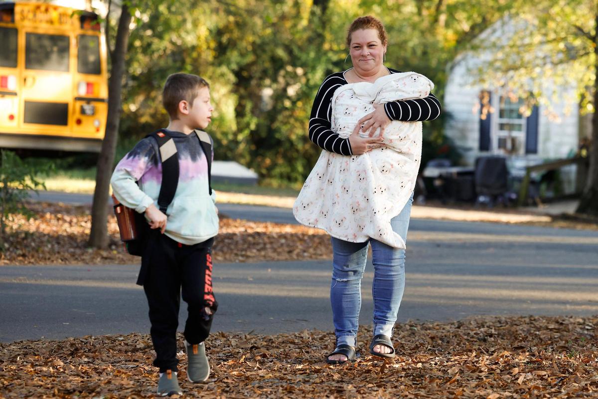 Erin O’Malley carries Lenni as she walks back to the house with her 6-year-old nephew Mateo Mengering from his bus stop.