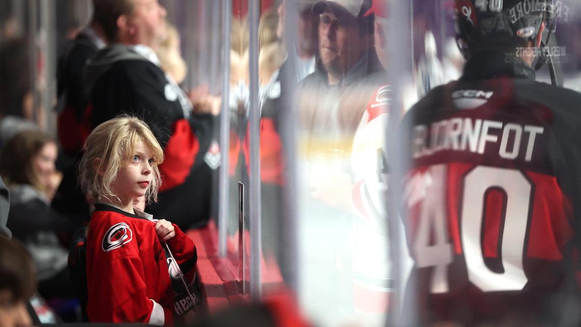Charlotte Checkers fan Riley Wilson, left, watches as members of the team skate past during a warmup prior to action against the Cleveland Monsters at Bojangles Coliseum in Charlotte, NC on Friday, October 18, 2024.
