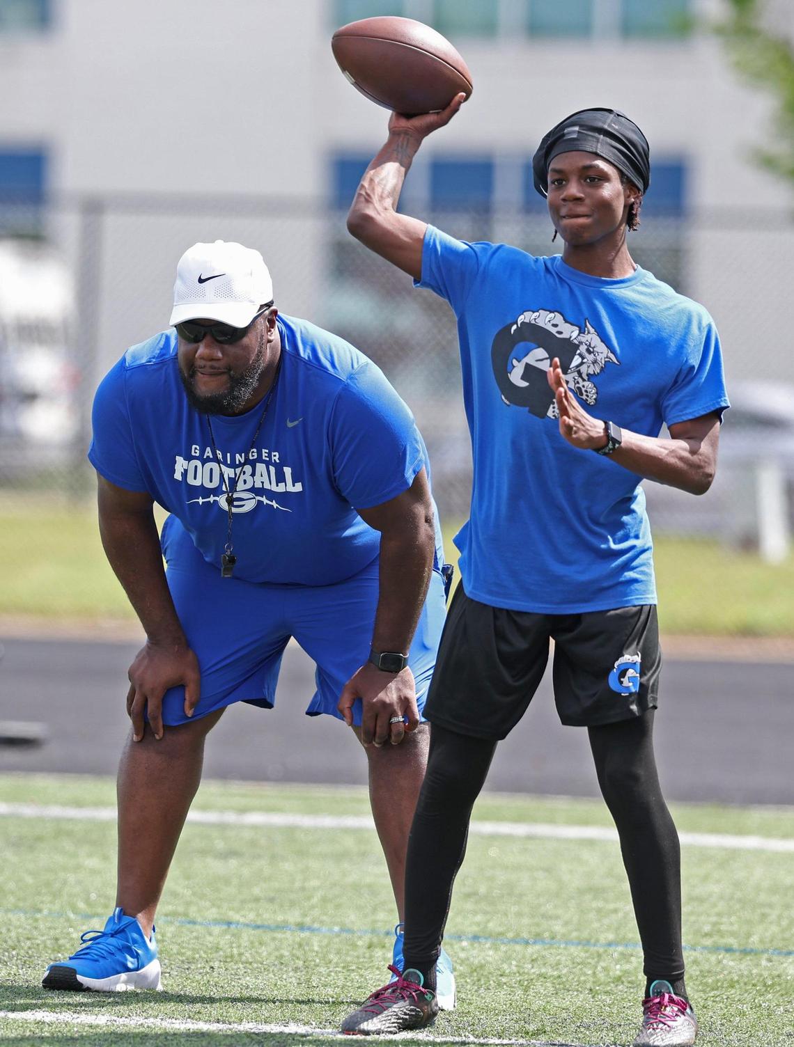 Garinger High School head football coach Jupiter Wilson, left, watches his players run through a workout on Tuesday, April 29, 2025. Garinger High School has been through dozens of coaches trying to turn the program around. Now, the former UNC football player is taking his turn.