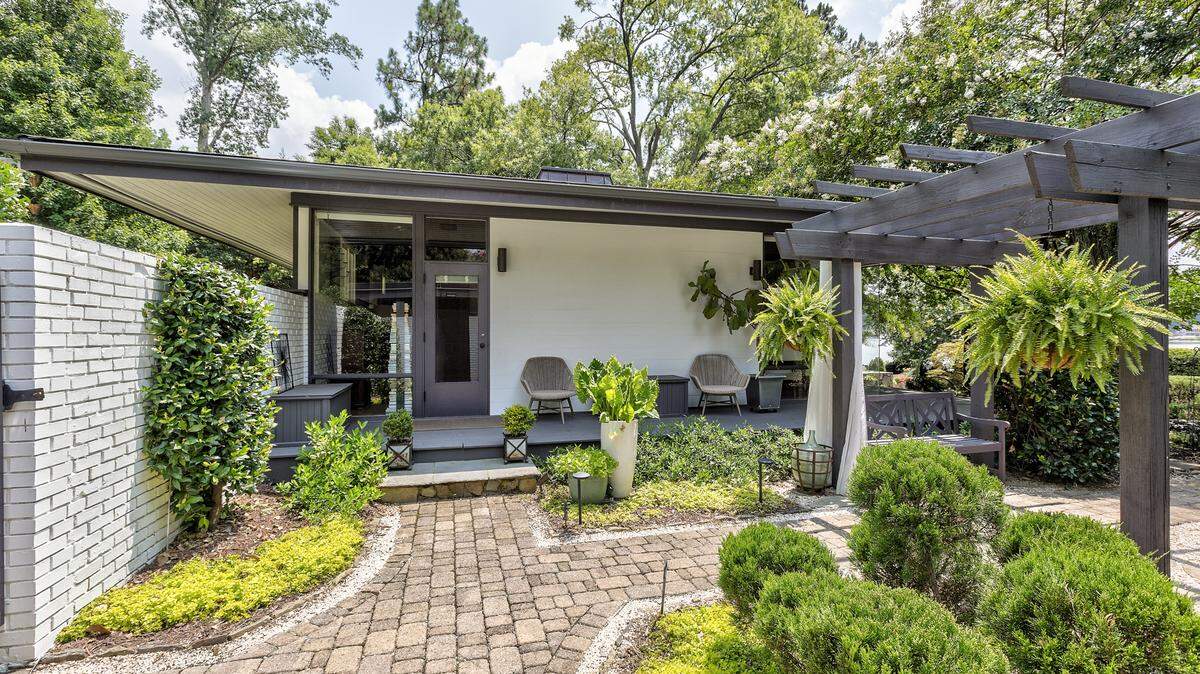 A low pitched roof with overhanging eaves shades the windows throughout this midcentury modern home designed by architect Murray Whisnant.
