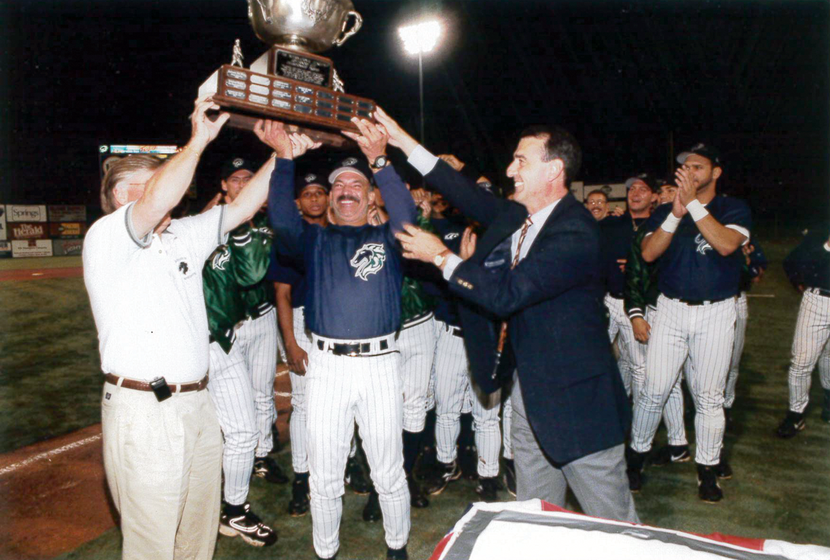 Charlotte Knights celebrate by raising the Governor’s Cup Trophy, after beating Durham in the 1999 International League finals. Shown are former Knights team owner Don Beaver (face obscured by trophy), former Knights manager Tom Spencer, and former International League president Randy Mobley. / Courtesy of the Charlotte Knights