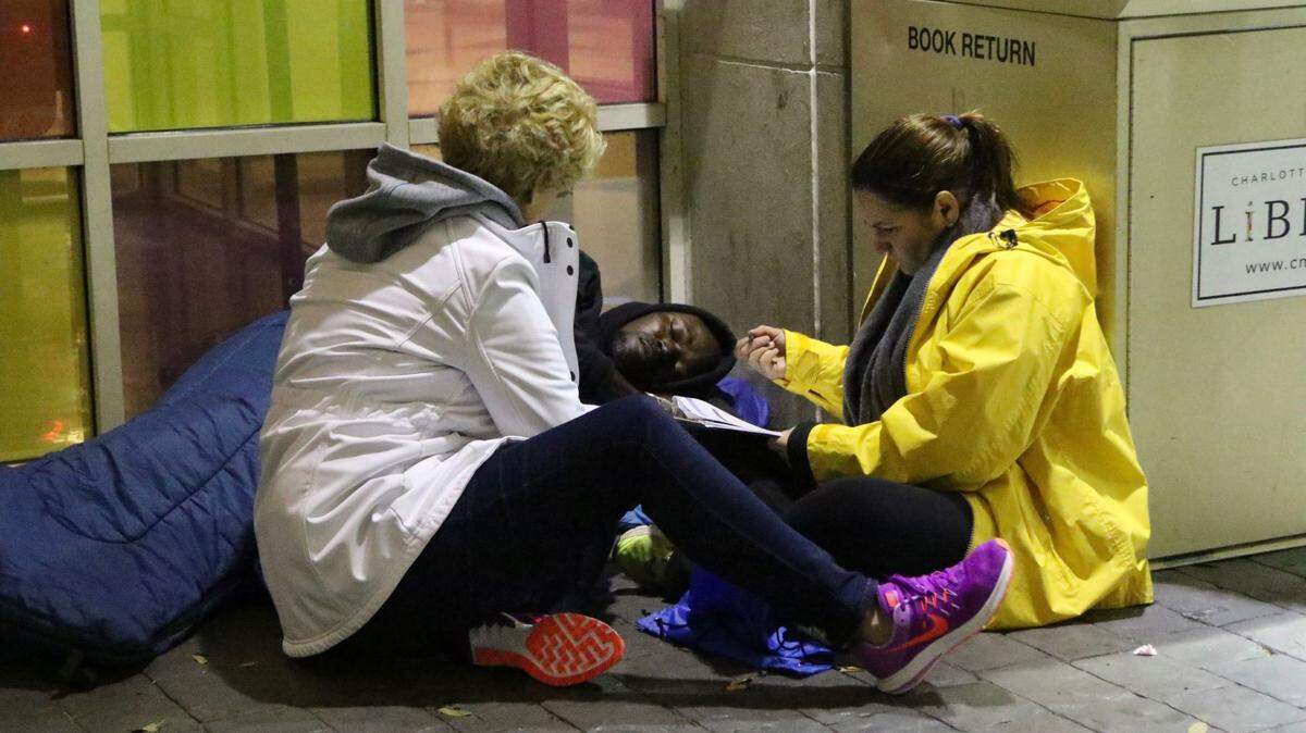 Homeless outreach employees speak to a homeless Charlotte resident outside of the library.