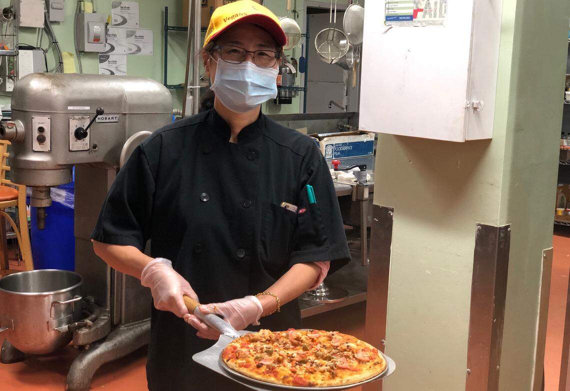 Loving Hut owner Si Blake holds the Meatless Lovers pizza, topped with marinara sauce, vegan mozzarella cheese, vegan ground beef, sausage, bacon, and black olives.