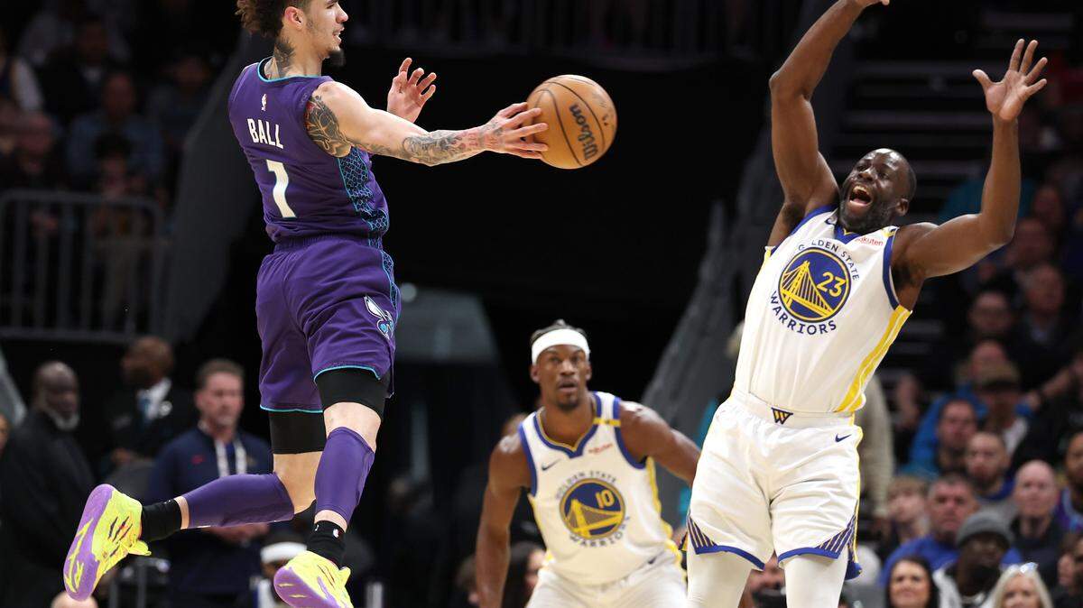 Charlotte Hornets guard LaMelo Ball, left, passes to a teammate as Golden State Warriors forward/center Draymond Green, right, reacts during action at Spectrum Center in Charlotte, NC on Monday, March 3, 2025.