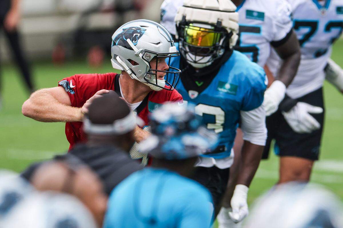 Panthers quarterback Sam Darnold, left, looks for a pass as defensive end Brian Burns approaches from behind during the Back Together practice in Gibbs Stadium at Wofford College on Saturday, July 30, 2022 in Spartanburg, SC.