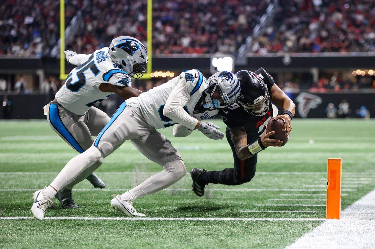Jan 5, 2025; Atlanta, Georgia, USA; Michael Penix Jr. (9) dives past Carolina Panthers cornerback Caleb Farley (31) for a touchdown in Sunday’s second quarter at Mercedes-Benz Stadium. Brett Davis-Imagn Images