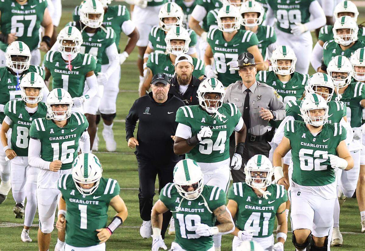 Charlotte 49ers head football coach Tim Albin, center, runs onto the field with his team prior to action against the North Texas on Friday, October 24, 2025 at Jerry Richardson Stadium.