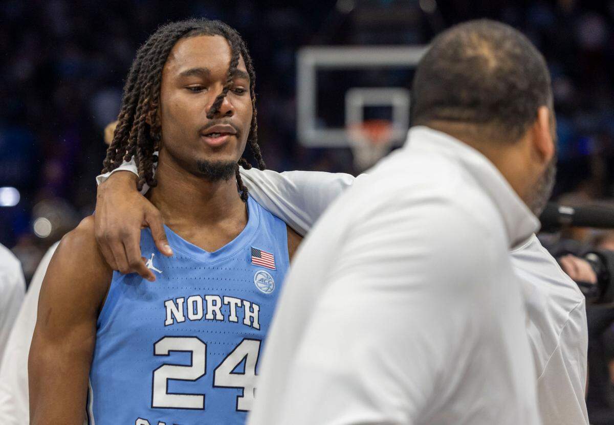 North Carolina forward Jae’Lyn Withers (24) is consoled by teammate Ty Claude (0) and assistant coach Sean May as he leaves the court following the Tar Heels’ 74-71 loss to Duke on Friday, March 14, 2025 during the semifinals of the ACC Tournament at Spectrum Center in Charlotte, N.C. Withers was charged with a lane violation with four seconda to play.