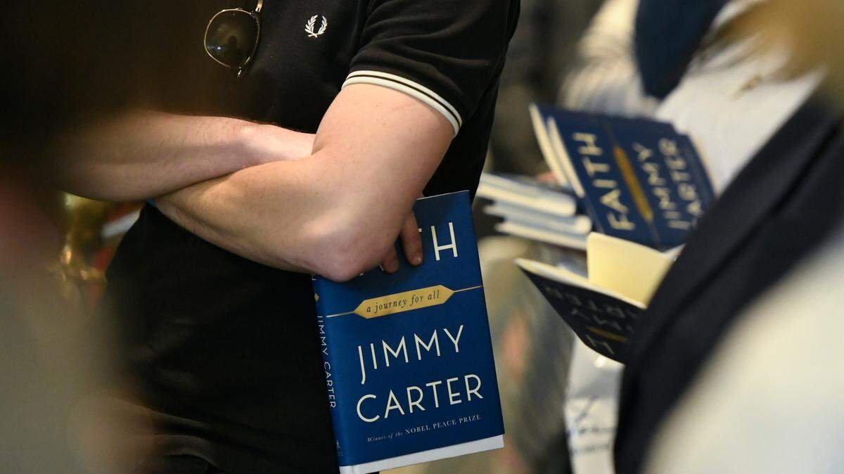 In this 2018 photo, patrons wait in line in Atlanta holding copies of a new book by former President Jimmy Carter as they wait for him to sign them. The book, titled “Faith: A Journey For All,” was the 30th one Carter had written.