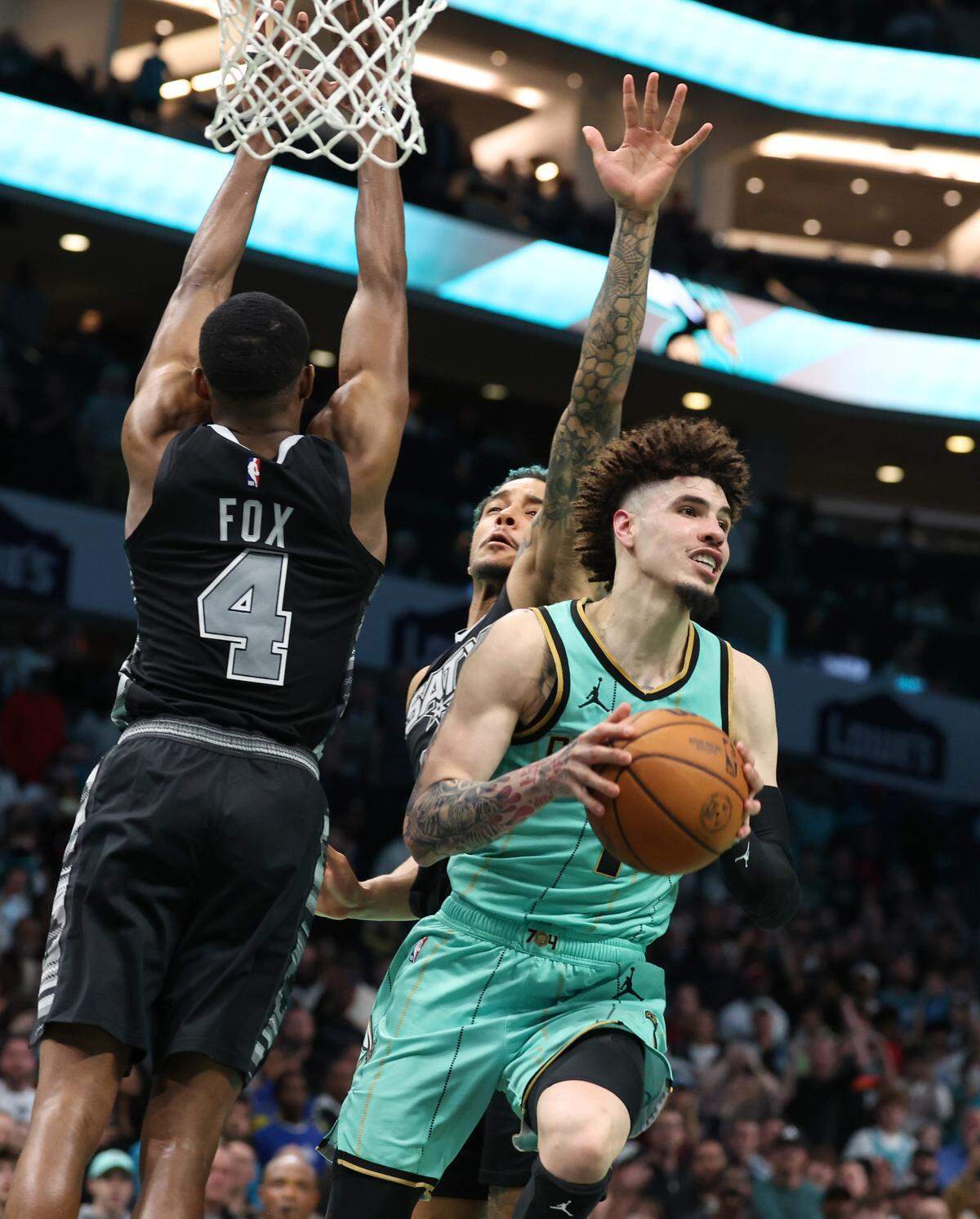 Charlotte Hornets guard LaMelo Ball, center, drives between San Antonio Spurs defenders guard De’Aaron Fox and forward Jeremy Sochan, right, to pass the ball out to forward Miles Bridges. Bridges released a three-point shot in the closing moments at Spectrum Center to give the team a 117-116 victory in Charlotte, NC.