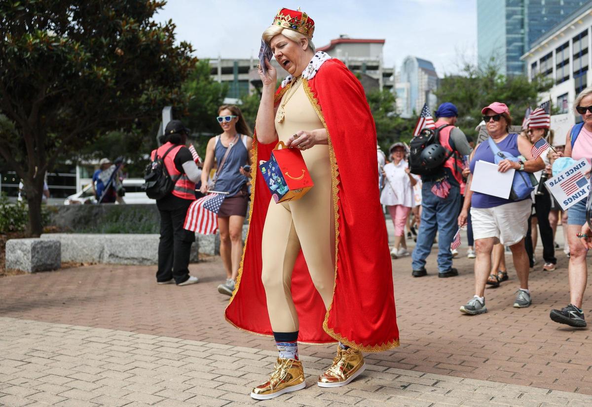 Amanda Hancock, with Indivisible, enters First Ward Park dressed as Donald Trump and pats her forehead with fake hundred dollar bills during the No Kings protest in Charlotte, NC on Saturday, June 14, 2025.