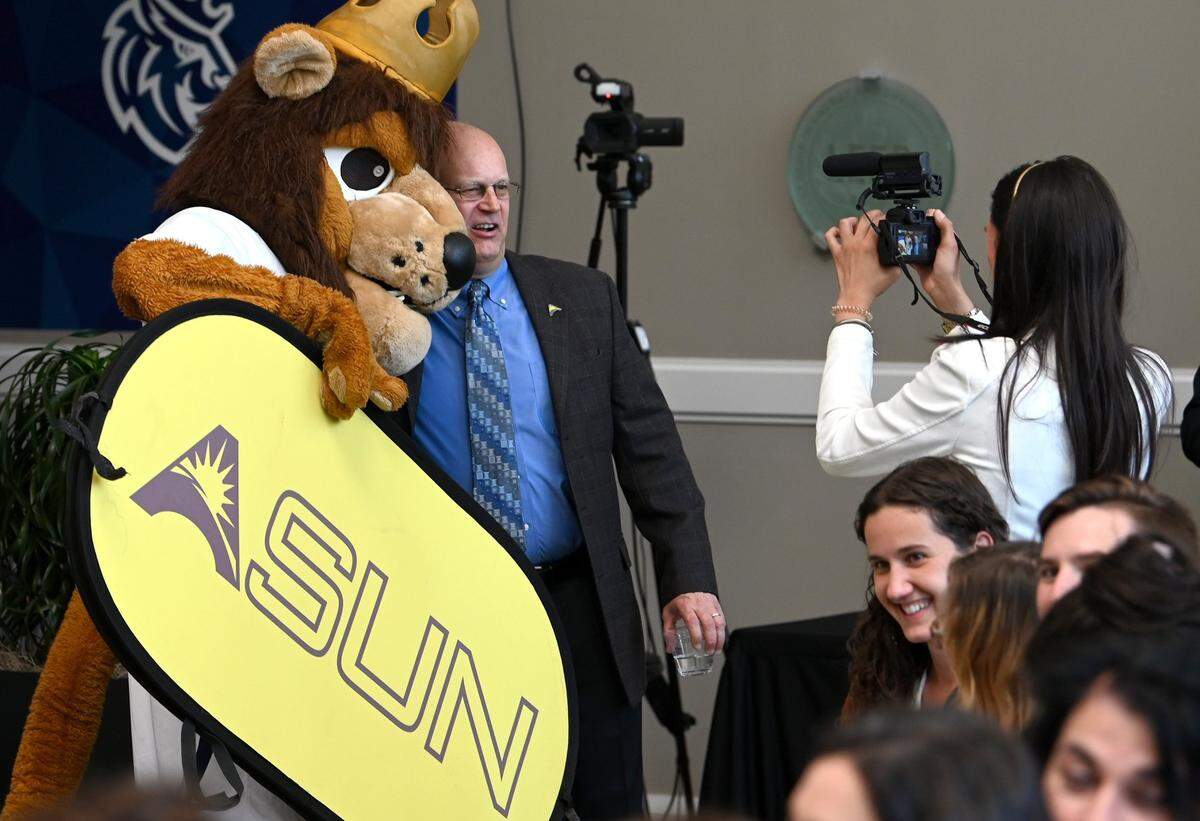 Queens mascot Rex the Lion poses with ASUN conference commissioner Ted Gumbart at a media event in May 2022, when it was announced that the private Charlotte college would be joining the league and transitioning into NCAA Division 1 competition.