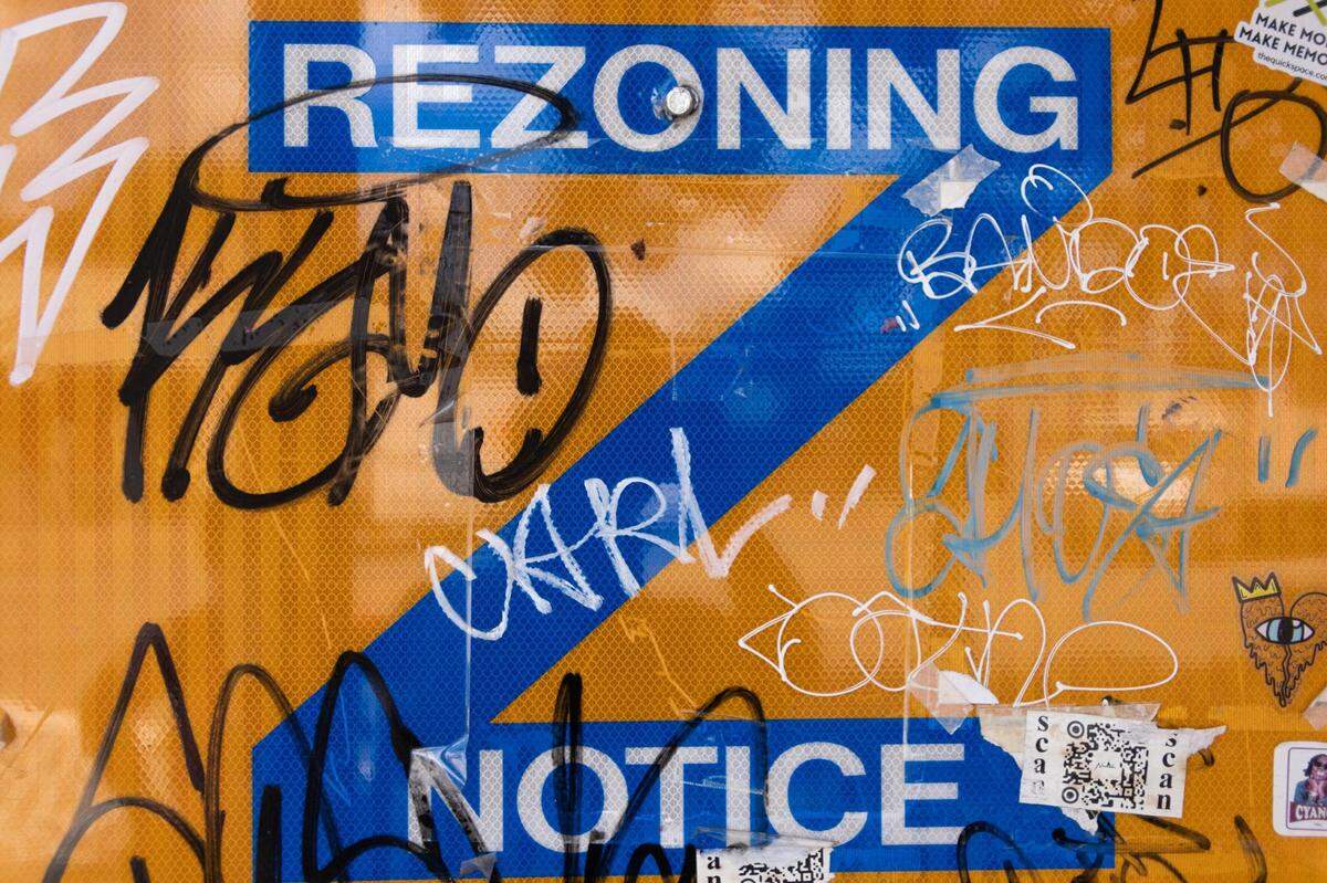 A vandalized re-zoning street sign stands at an intersection in Plaza Midwood.