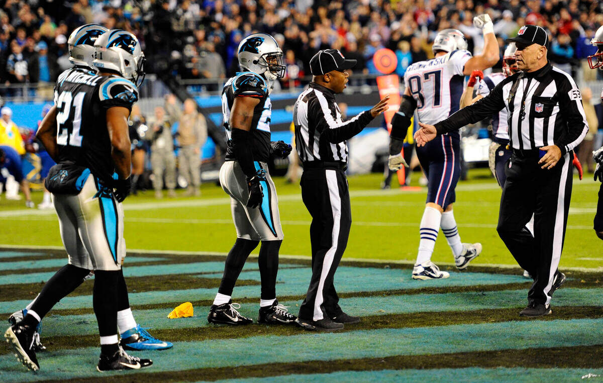 NFL back judge Terrence Miles (111) (center) talks with umpire Garth DeFelice (53) after Miles threw a flag for pass interference on the last play in the Carolina Panthers-New England Patriots game at Bank of America Stadium on November 18, 2013. The flag was ultimately waved off, as Tom Brady’s intercepted pass was deemed to have been uncatchable by tight end Rob Gronkowski (87). The Panthers won, 24-20.