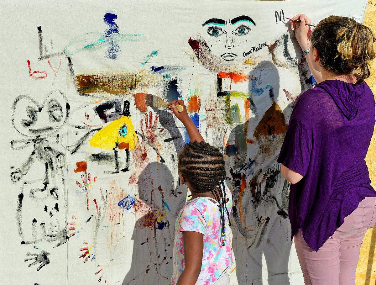 Zaria Campbell, left, and Ava Haire work on a mural, one of many displayed a past BOOM festival in Plaza Midwood. Charlotte's annual showcase of contemporary and experimental art seeks to transform the way art is made and shared in the Queen City. 