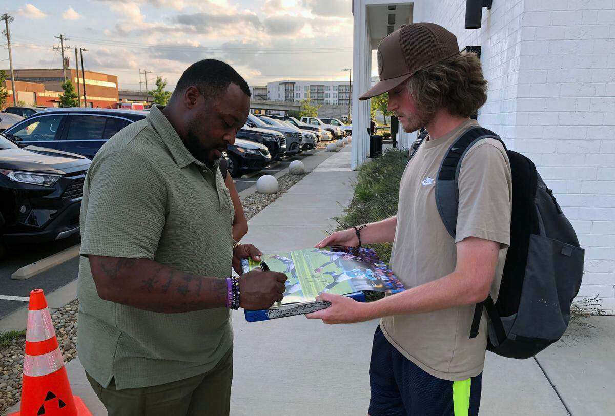 Former Carolina Panthers fullback Mike Tolbert (left) stops to sign an autograph for a fan outside the Independent Picture House in Charlotte, NC on Thursday, July 24, 2025. Tolbert and other stars from the Carolina Panthers’ 2015 Super Bowl team were attending The Charlotte Observer’s premiere of the documentary “SUPER MEN.”
