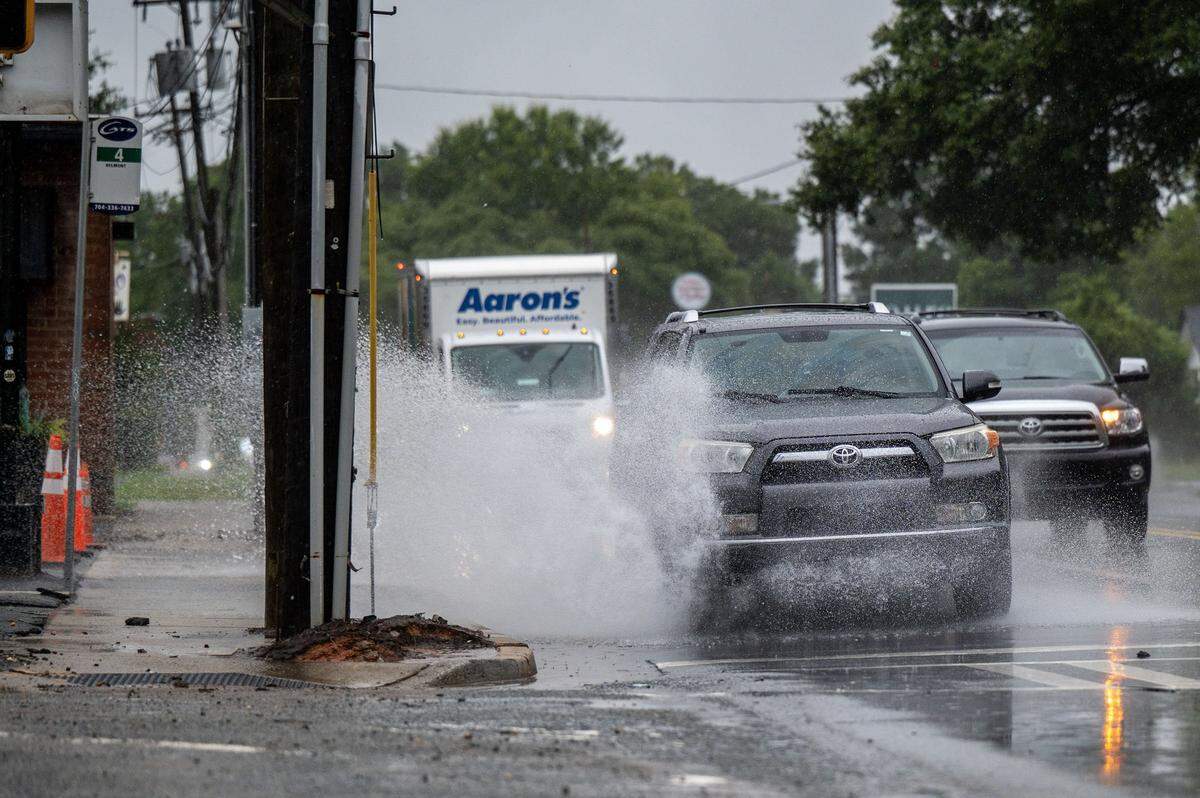 Cars drive through a puddle on The Plaza in Charlotte, NC, Tuesday August 5, 2025. Heavy rains flooded Charlotte-area roads on Tuesday, and daily rain dumps and unseasonably cool temperatures are expected all week, National Weather Service forecasters said Tuesday.