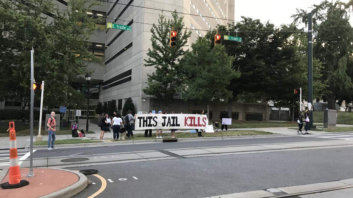 Activists held signs and banners outside the Mecklenburg County Jail on East Trade Street in July. Four men died at the jail in two months, and the activists called for answers and change.